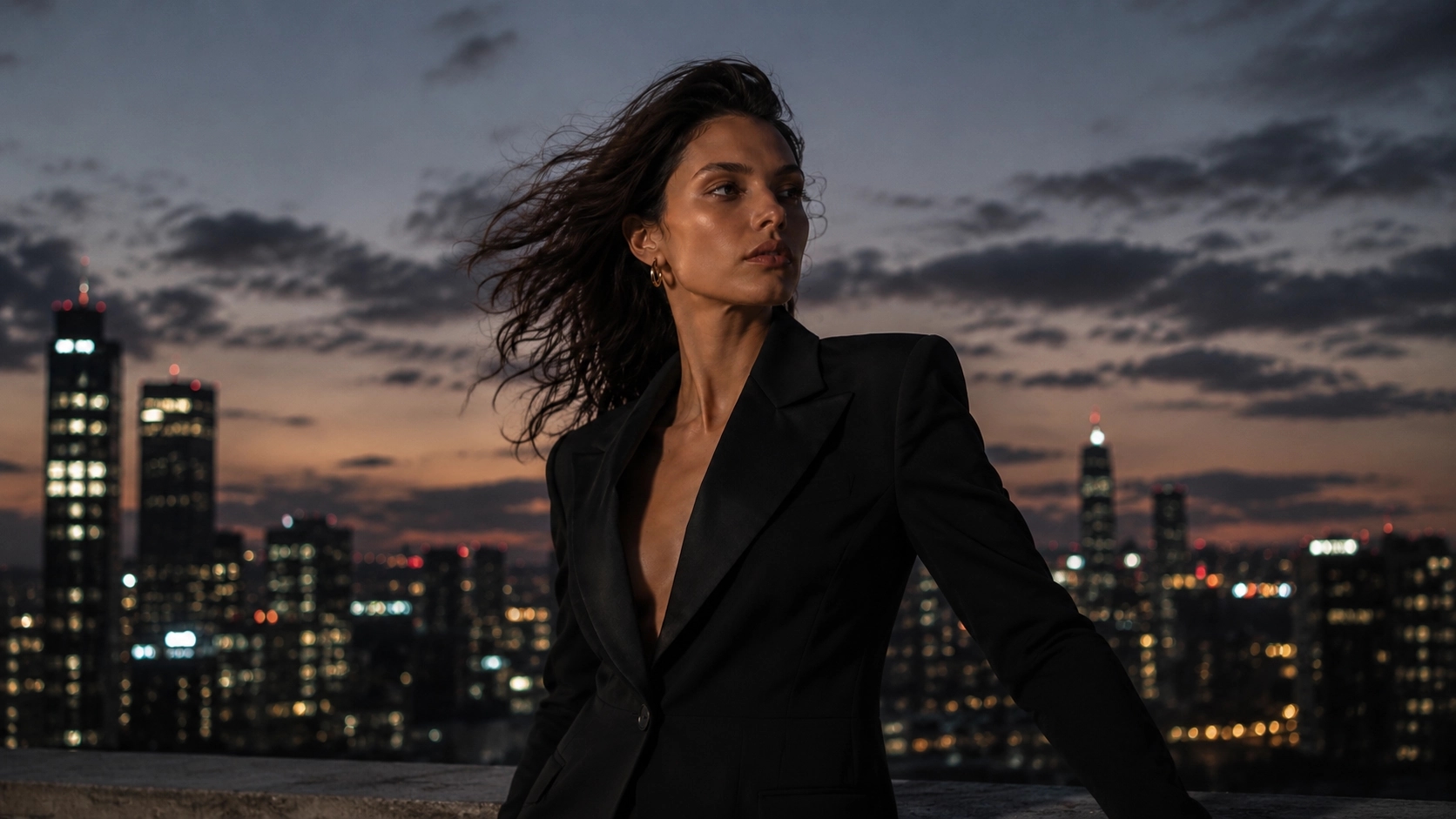 Model in structured black blazer on rooftop at blue hour